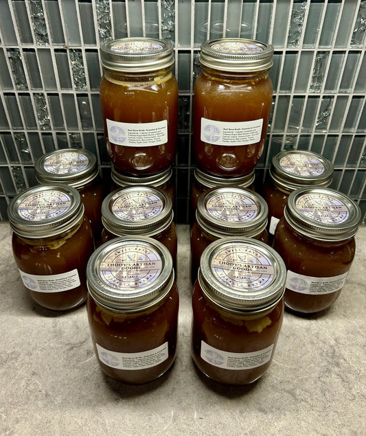 Jars of Thody's Artisan Beef Bone Broth arranged on a shelf, with clear labels on each jar.